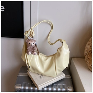 Detail of yellow crescent shoulder bag with soft pleats and cute plush bear charm