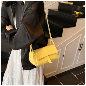 Side view of bright yellow litchi pattern leather bag worn by model on stairs