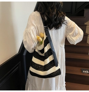 Détail du sac cabas en maille rayé noir et blanc avec bandoulière en cuir sur modèle