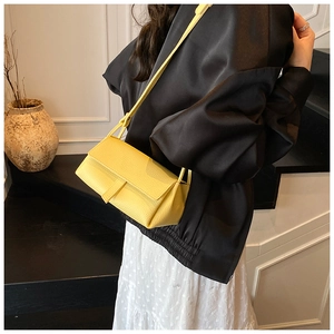 Close-up of vibrant yellow lychee pattern leather flap crossbody bag worn by model