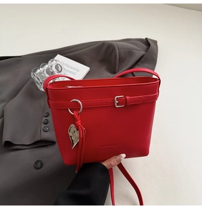 Dettaglio borsa a secchiello rossa in pelle martellata con fibbia e ciondolo a cuore