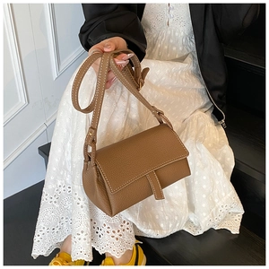 Brown litchi leather pillow bag with white contrast stitching and adjustable strap detail