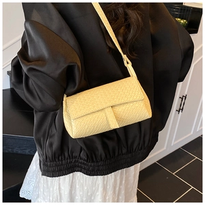 Detail showing creamy yellow woven texture handbag styled with a black jacket