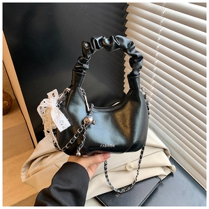 Detail of black pleated cloud bag with lace bow pendant and chain shoulder strap