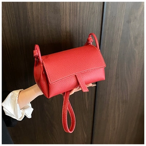 Detail of red lychee grain leather bag featuring white contrast stitching and flap closure