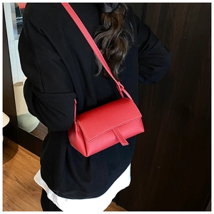Rear view of a red lychee pattern leather crossbody bag worn on a person in warm lighting