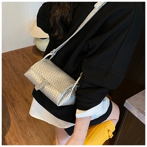 Detailed close-up of metallic silver woven texture and flap closure on a crossbody bag