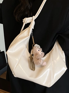 Cream patent leather crescent shoulder bag with knot strap and plush bear charm