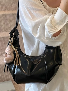Glossy black patent leather crescent underarm bag with a cute plush bear charm