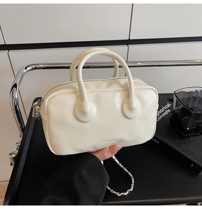 Close-up of minimalist cream leather handbag with CLEAR K logo and chain strap