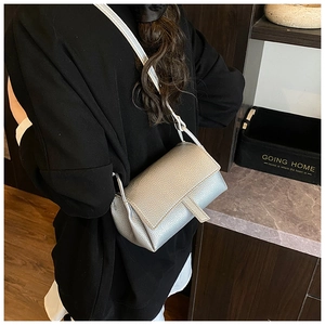 Detail of silver lychee texture small square bag with flap and metal finish shown on shoulder