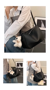 Detail of black pebbled leather Boston bag featuring a plush bear charm and adjustable strap