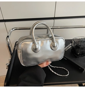 Detail view of metallic silver boston bag with woven chain strap and brand lettering