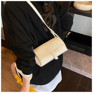 Detail view of cream woven shoulder bag with adjustable strap in a lifestyle setting