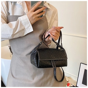 Detail of black woven handbag with white contrast stitching and faux leather texture