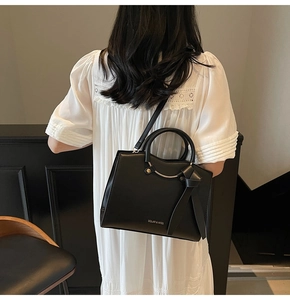 Detailed view of the black PU leather tote bag featuring gold ring and brand logo