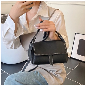 Close-up of black lychee grain leather pillow bag featuring white contrast stitching details
