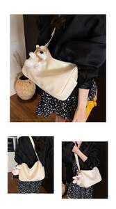 Close-up of cream leather shoulder bag with lychee texture and cute teddy bear pendant