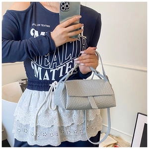 Detail of grey crocodile pattern handbag with magnetic flap and slim shoulder strap