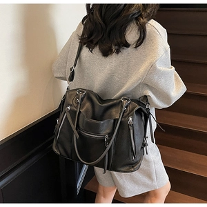Rear view of a model wearing the black pebbled leather tote bag on a brown staircase