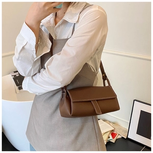Detailed close-up of brown lychee leather pillow bag with elegant white contrast stitching