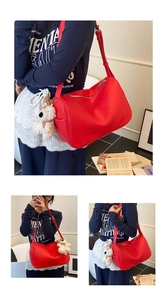 Close-up of a stylish red leather shoulder bag featuring a cute white plush bear charm