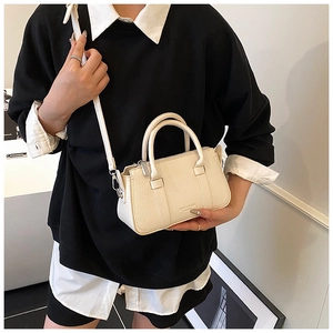 Detail of a creamy beige lychee grain leather handbag with silver hardware and logo