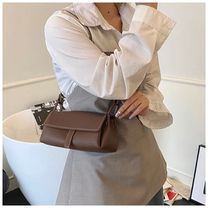 Detail view of brown lychee grain leather handbag with contrast stitching on model