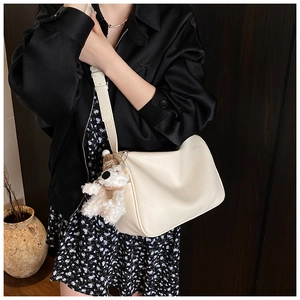 Close-up of ivory pebble leather shoulder bag with cute plush bear pendant accessory