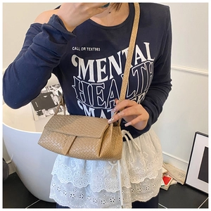 Mirror selfie showing the compact khaki woven leather shoulder bag with a crossbody strap