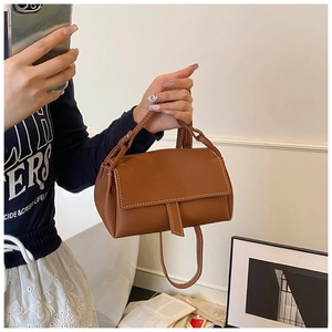 Detail view of brown lychee grain leather handbag featuring white contrast stitching