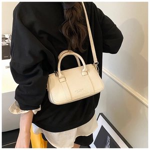 Detail of beige lychee textured leather crossbody bag with logo and top handle