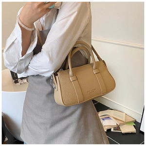 Close-up of beige lychee texture leather handbag with elegant handles and metal buckles