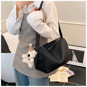 Detail of black lychee grain leather underarm bag with cute white bear charm accessory