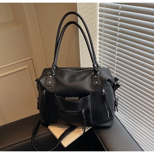 Detail of black pebbled leather texture and silver metallic hardware on the bag