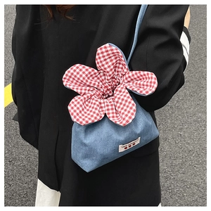 Detail of a denim drawstring bag with red plaid flower top and 'YES HONEY!' label