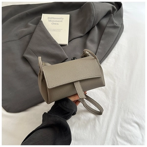 Detail view of lychee pattern leather and vertical buckle on the grey crossbody pillow bag