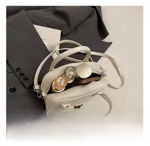 Détails de l'intérieur du sac blanc montrant le rangement pour maquillage et parfum