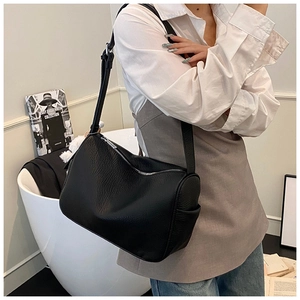 Close-up of black pebble leather shoulder bag on a model in a minimalist setting