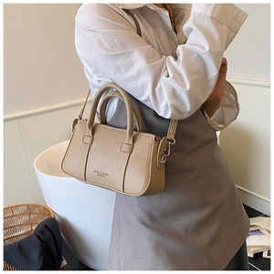 Close-up of khaki lychee grain leather handbag with handles and detachable metal strap