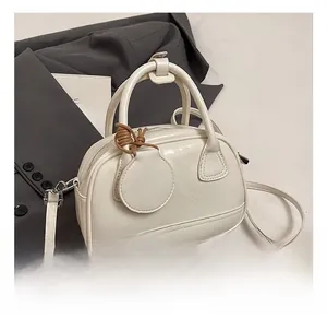 Détail macro du sac bowling en cuir blanc crème élégant avec des ferrures argentées