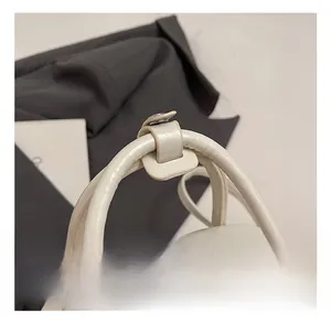 Détail du sac à main en cuir blanc cassé montrant les doubles poignées et les boucles en métal