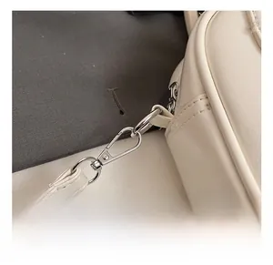 Gros plan détaillé des crochets métalliques et de l'anneau D sur un sac beige en cuir