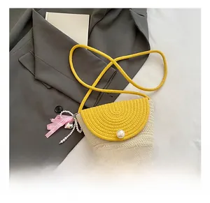 Detail of woven straw crossbody bag featuring a pearl clasp and pink checkered ribbon