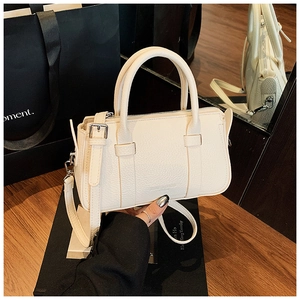 Detailed macro view of white lychee textured leather on a chic mini Boston handbag