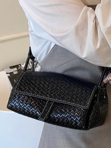 Minimalist black woven leather shoulder bag with white contrast stitching and flap closure