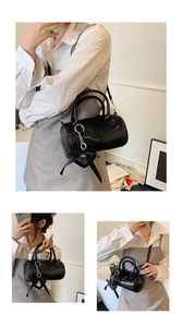 Detail view of black cylinder bag featuring a silk bow and silver metal chain accessory