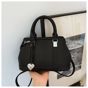 Detailed macro view of black lychee leather bag with silver heart charm and metal accents