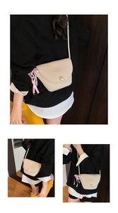 Detail of straw woven crossbody bag with spiral texture, pearl buckle, and pink ribbon charm