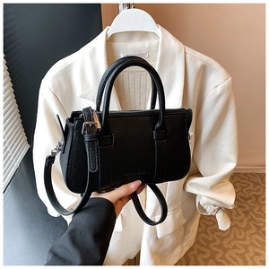 Close-up of black lychee grain leather handbag featuring dual handles and brand embossing